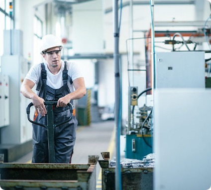 A warehouse employee at work is pushing a trolley