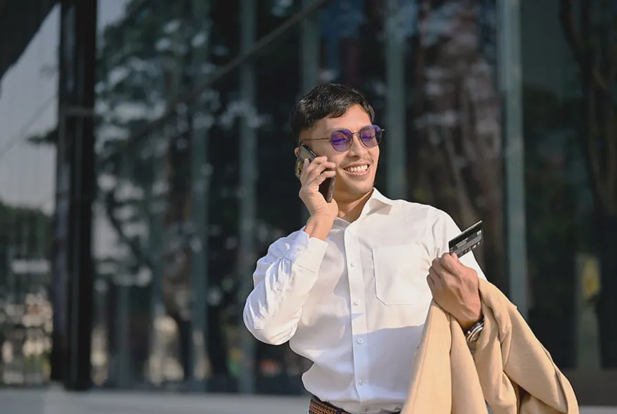 Man talking on a phone outside, holding a credit card