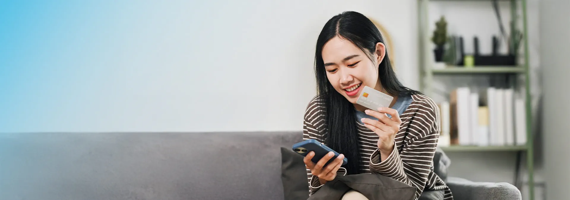 A person holding a credit card and a phone