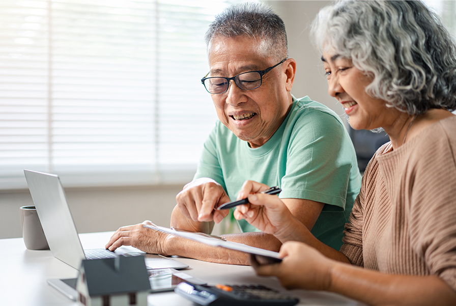 Senior couple reviewing financial documents together at a table with a laptop and calculator